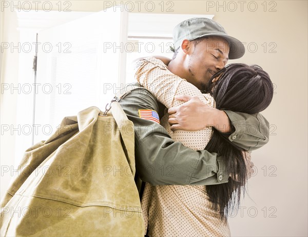 Returning soldier kissing wife in hallway