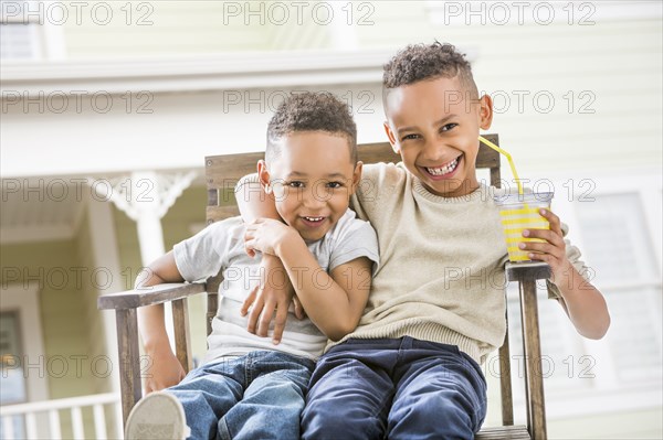 Brothers hugging in armchair in backyard