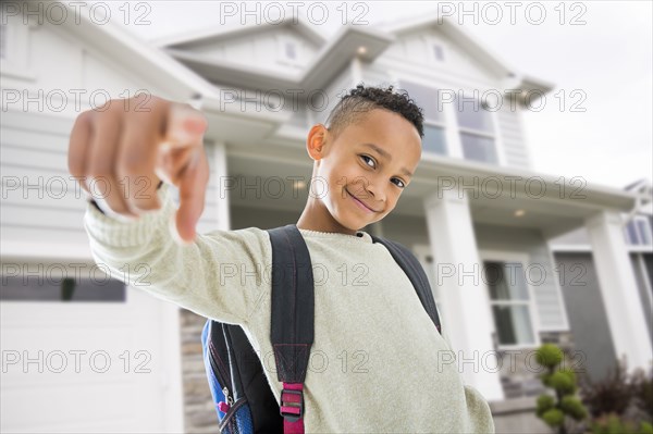 Black boy in backpack pointing on front lawn