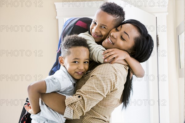 Mother and sons hugging at door