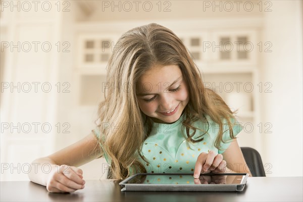 Caucasian girl using digital tablet at table