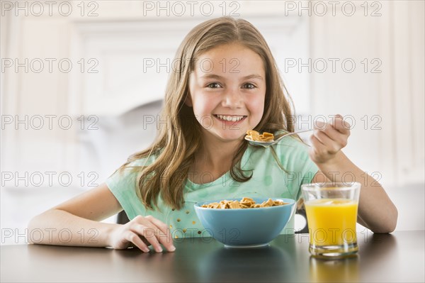 Caucasian girl eating cereal at table