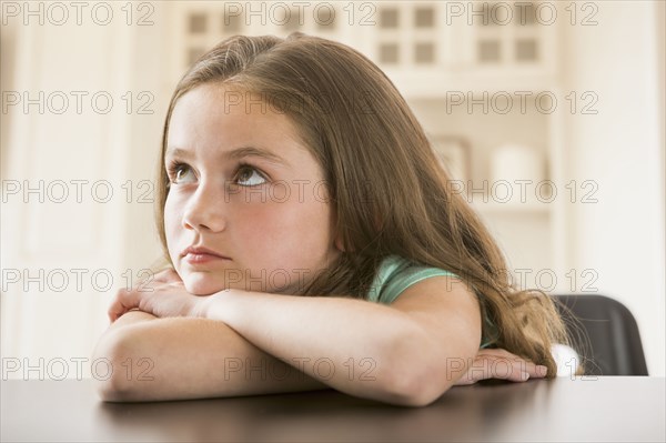 Bored Caucasian girl leaning on table
