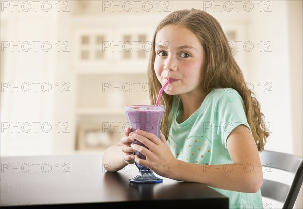 Caucasian girl drinking milkshake in kitchen