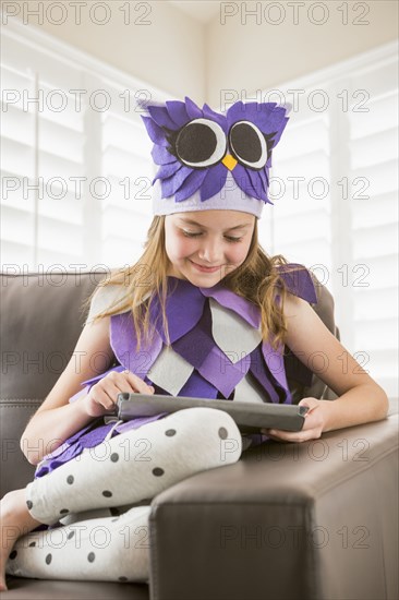 Caucasian girl in costume using digital tablet on sofa