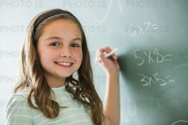 Caucasian girl doing math problems on chalkboard