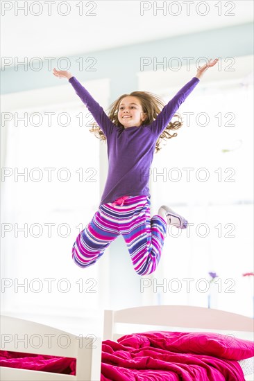 Caucasian girl jumping on bed