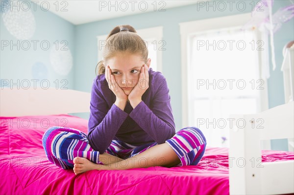 Pouting Caucasian girl sitting on bed