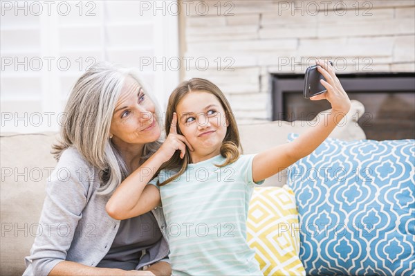 Caucasian grandmother and granddaughter taking selfie with cell phone