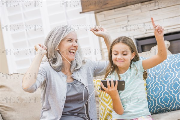 Caucasian grandmother and granddaughter listening to cell phone