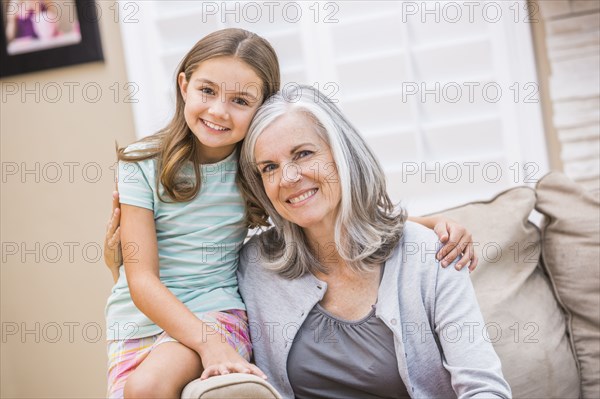 Caucasian grandmother and granddaughter hugging on sofa