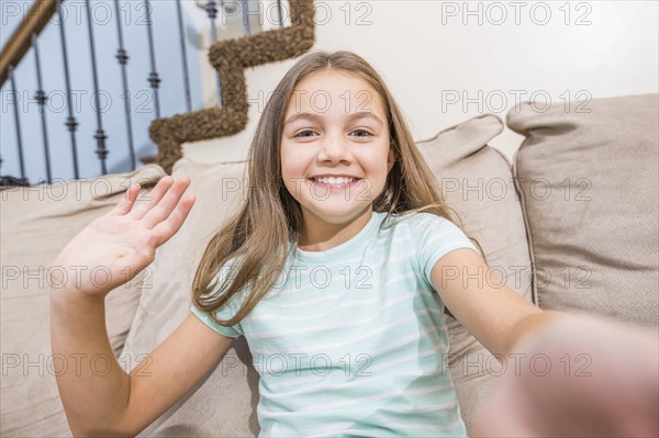 Caucasian girl taking selfie on sofa