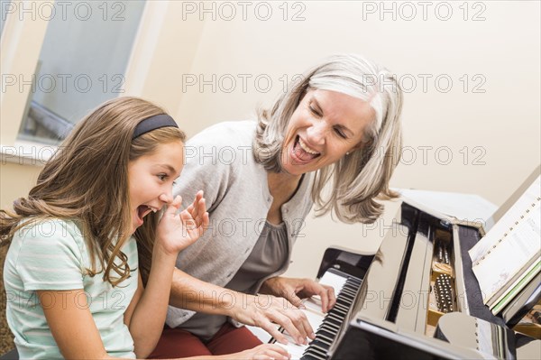 Caucasian grandmother and granddaughter playing piano