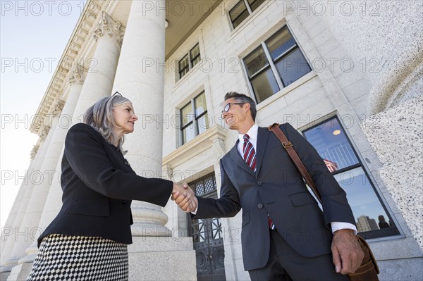 Business people shaking hands courthouse