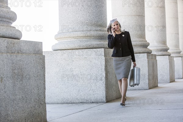 Caucasian businesswoman talking on cell phone under columns