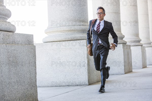 Mixed race businessman walking under columns