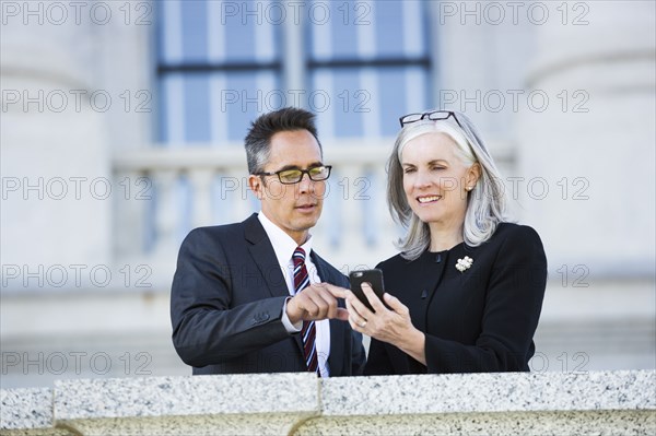 Business people using cell phone outside courthouse