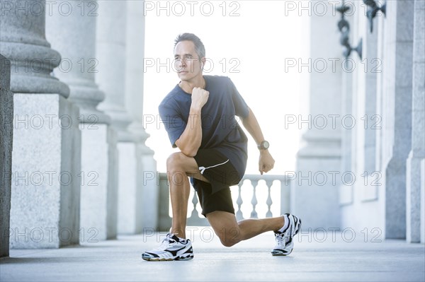 Mixed race man stretching outside courthouse