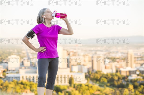 Caucasian woman drinking water bottle on urban hilltop