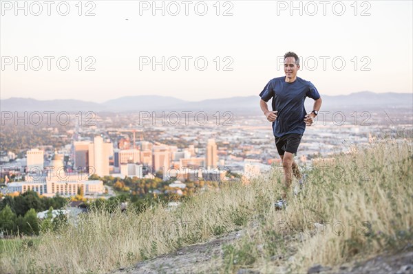 Mixed race man running on hilltop over Salt Lake City