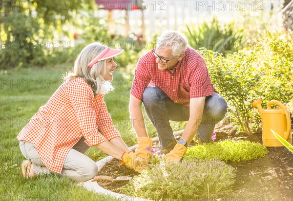 Caucasian couple gardening in backyard