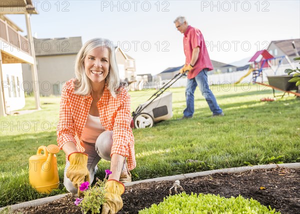 Caucasian couple gardening in backyard