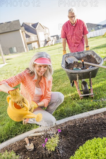 Caucasian couple gardening in backyard