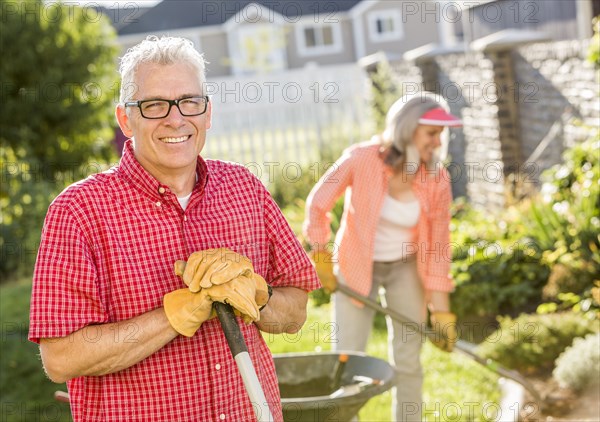 Caucasian couple gardening in backyard