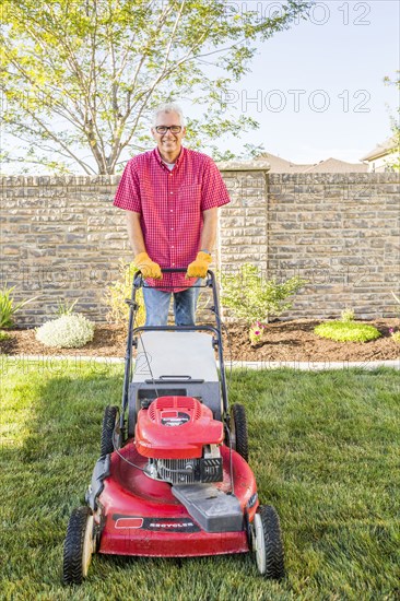 Caucasian man mowing lawn in backyard