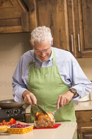Caucasian man carving chicken in kitchen