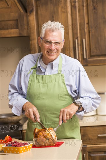 Caucasian man carving chicken in kitchen