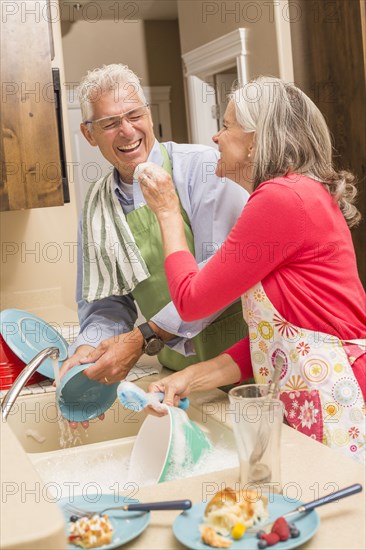 Caucasian couple washing dishes in kitchen