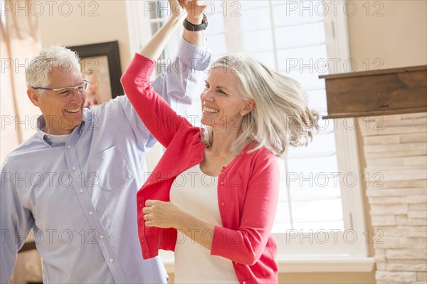 Caucasian couple dancing in living room