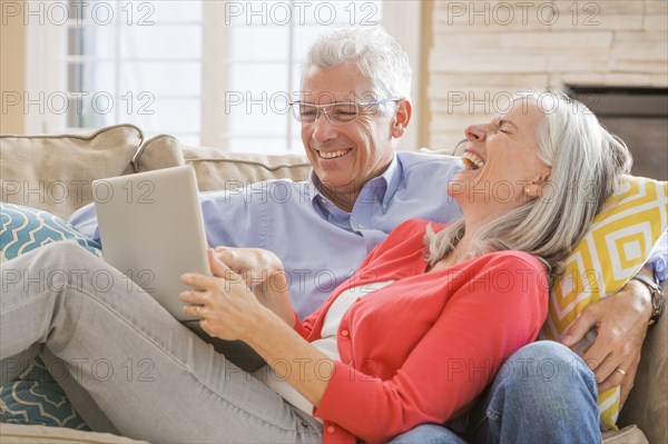 Caucasian couple using laptop on sofa