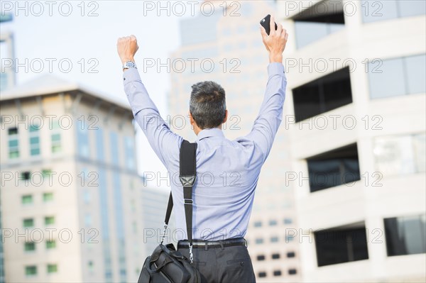 Mixed race businessman cheering outdoors