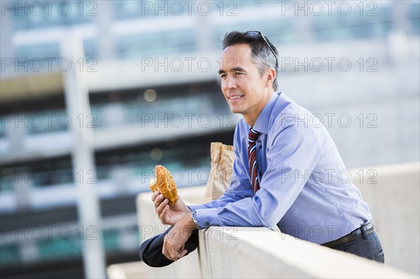 Mixed race businessman eating on urban rooftop