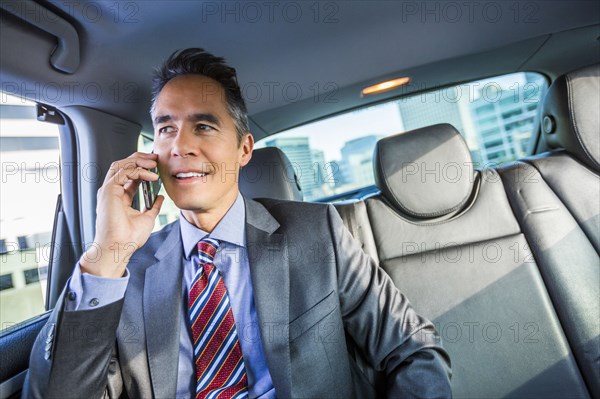 Mixed race businessman talking on cell phone in car