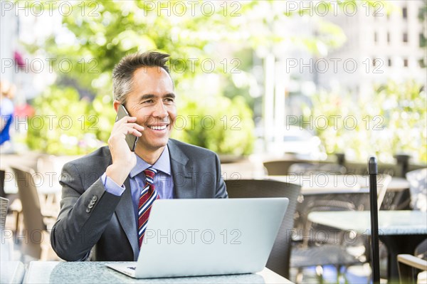 Mixed race businessman talking on cell phone in cafe