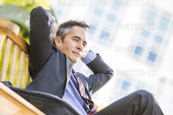 Mixed race businessman sitting outdoors