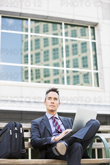 Mixed race businessman using laptop outdoors