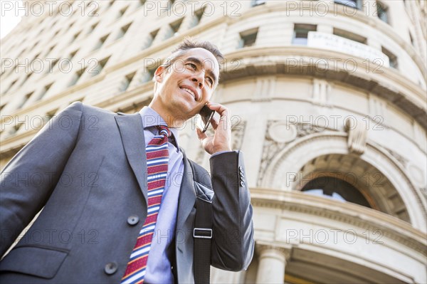 Mixed race businessman talking on cell phone outdoors