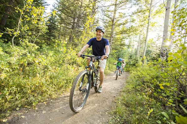 Caucasian father and children riding mountain bikes