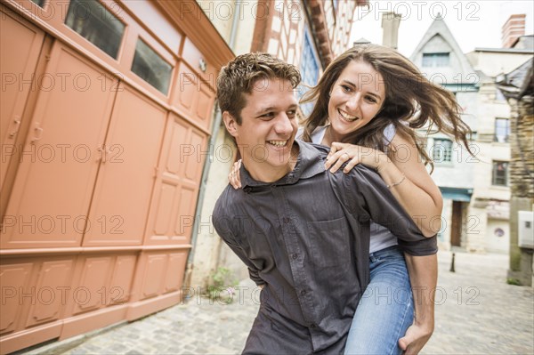 Caucasian man carrying girlfriend piggyback in village