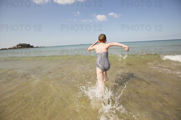 Caucasian girl splashing in waves on beach