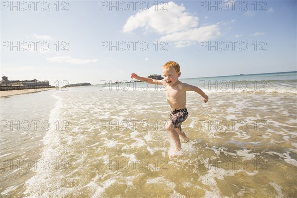 Caucasian boy playing in waves on beach