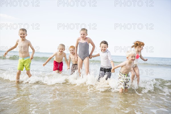 Caucasian children playing in waves on beach