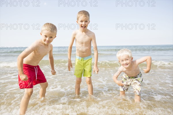 Caucasian boys playing in waves on beach