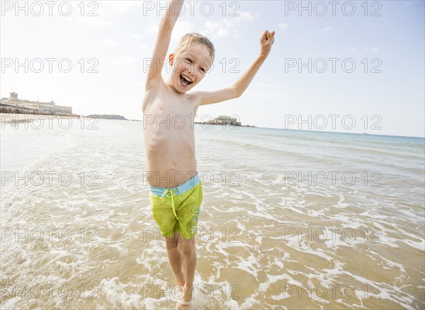 Caucasian boy playing in waves on beach
