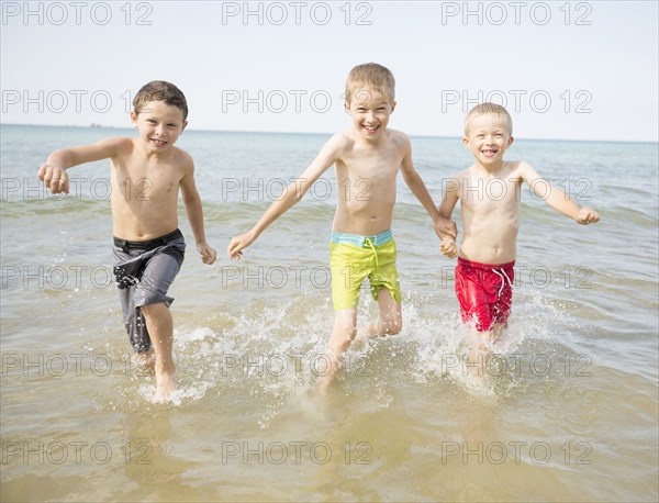 Caucasian boys playing in waves on beach