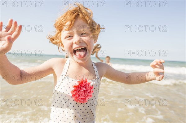 Caucasian girl playing in waves on beach